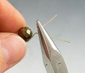 pliers twisting wire around a bead